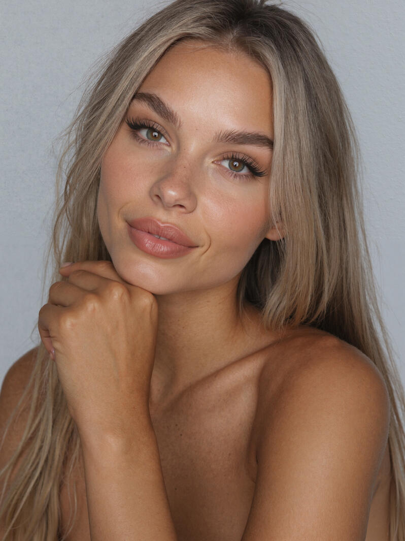 Close-up portrait of Mia Liorvian with hand under chin against a gray studio backdrop.